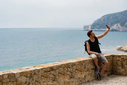 man seating by the sea landscape taking a selfie 2023 11 27 05 05 50 utc